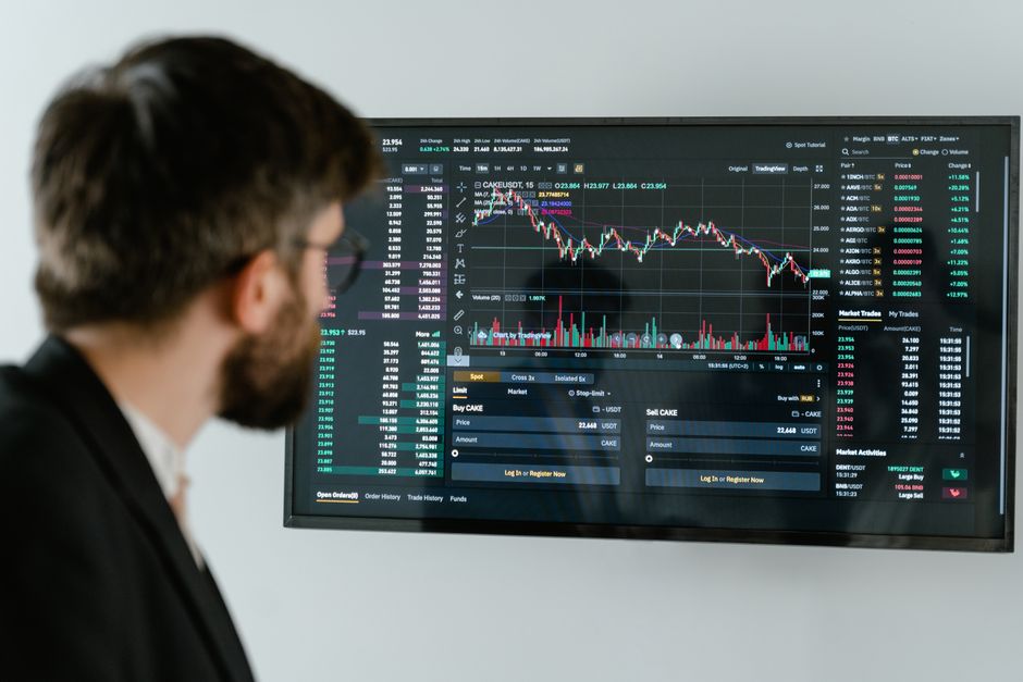 A businessman in a suit looks at a screen displaying stock market charts and data analysis.